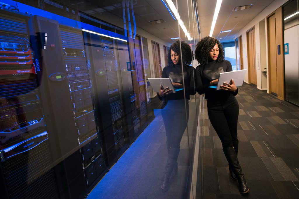 Your Managed Hosting Provider May Have Already Addressed the Vulnerability - Woman standing with a laptop by physical database servers